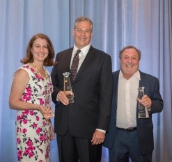 two men holding awards next to woman
